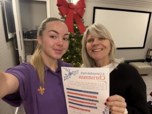 Two team members smiling and holding up a sheet of paper that says 'A Cavendish Park Christmas', at Cavendish Park in Evesham.