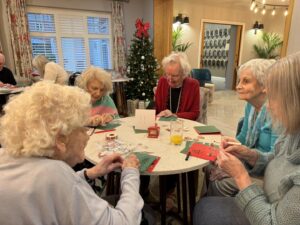 residents sit around a table decorating christmas cards at Cavendish Park Care Home, in Evesham.