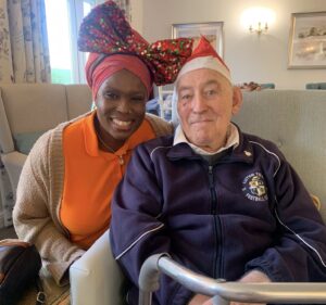 A man and a woman sat smiling wearing Christmas headwear at Milton Ernest Hall in Bedford.