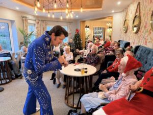 A man dressed as Elvis Presley sings to residents wearing santa hats at Cavendish Park in Evesham.