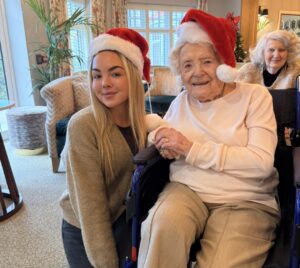 Team member and resident sat smiling together wearing santa hats at Cavendish Park in Evesham.
